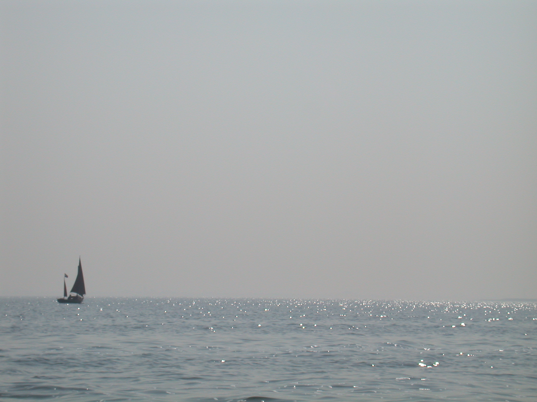 water water's edge boat sail sailing sailboat sail-boat small in the distance