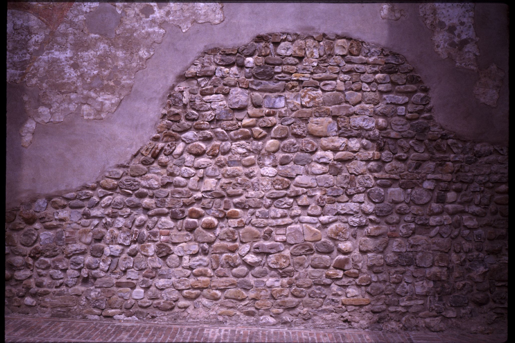 brick rock stone wall with exposed plaster layer