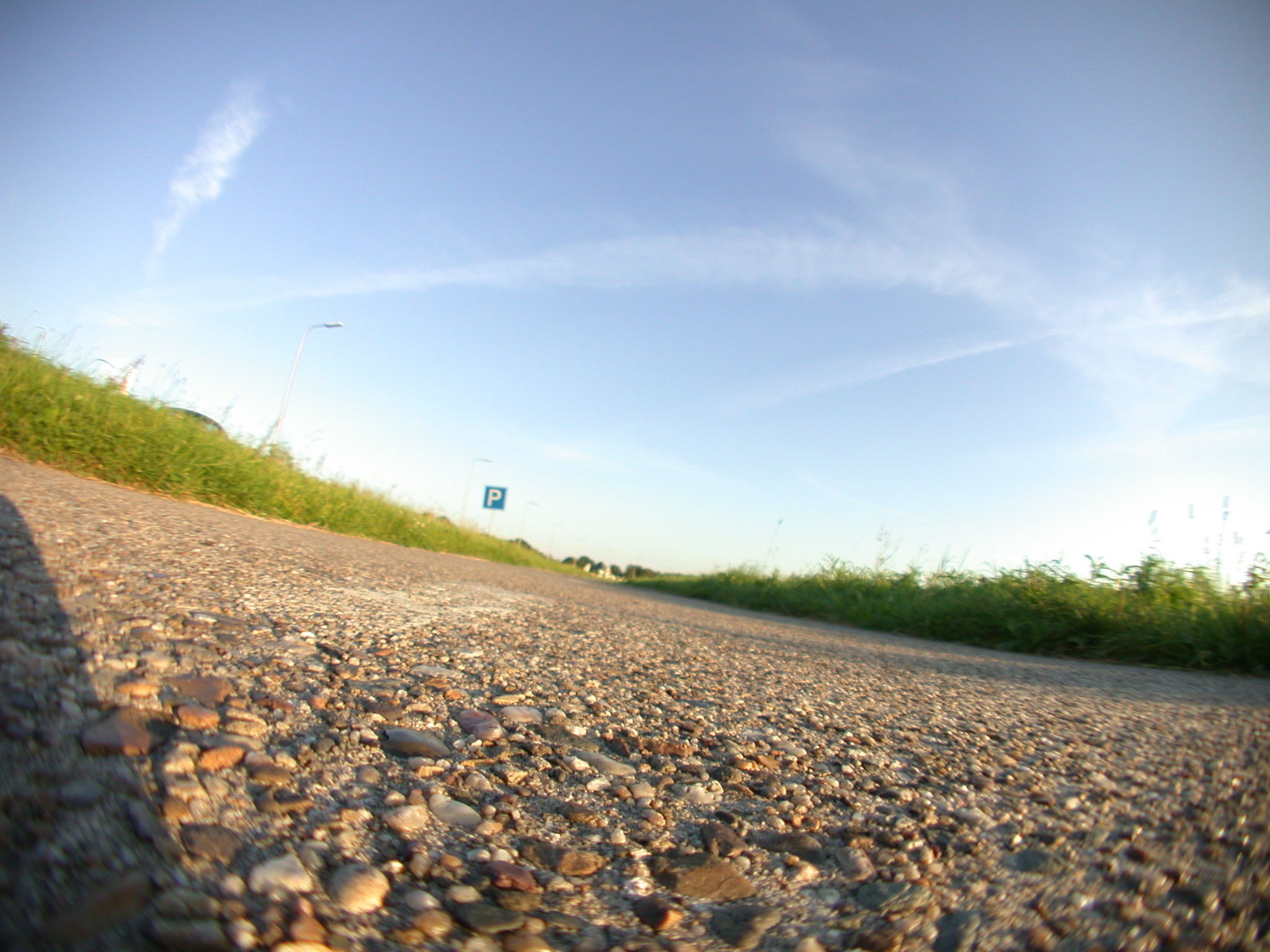 road ground close to the sign gravel pebble pebbles bush