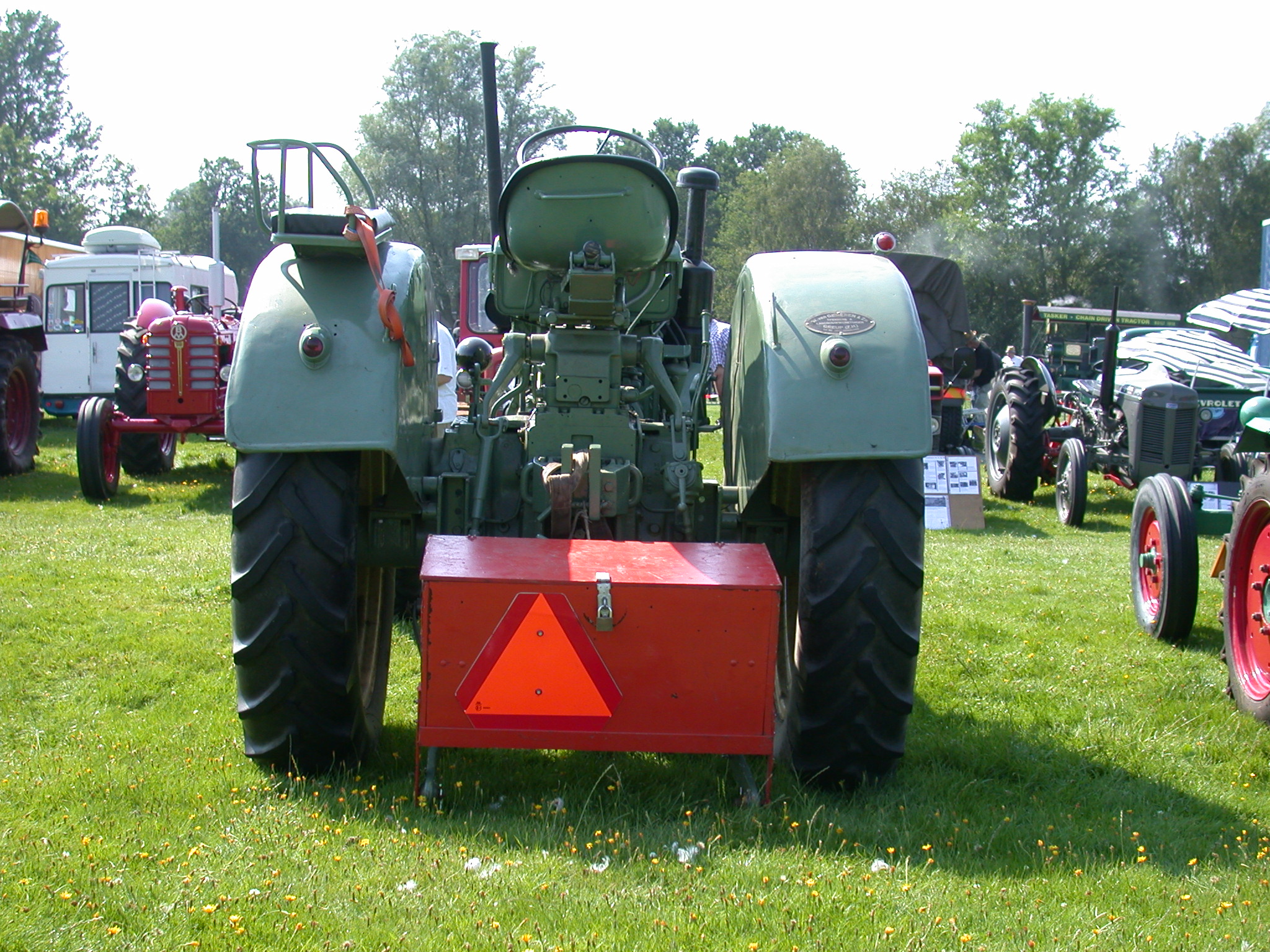 tractor rear view carshow grass big wheels green bright sunny day box booth trunk