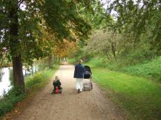 tabus characters humanoids walk in the park mother child buggy children back path river trees walking woman baby chesnut