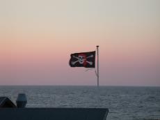 pirate flag pirateflag aaaargh me old matey ship jolly roger skull strangely enough waring a red bandana waterline horizon