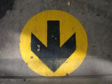 sign arrow pointing down this way detour round black painted on concrete yellow black